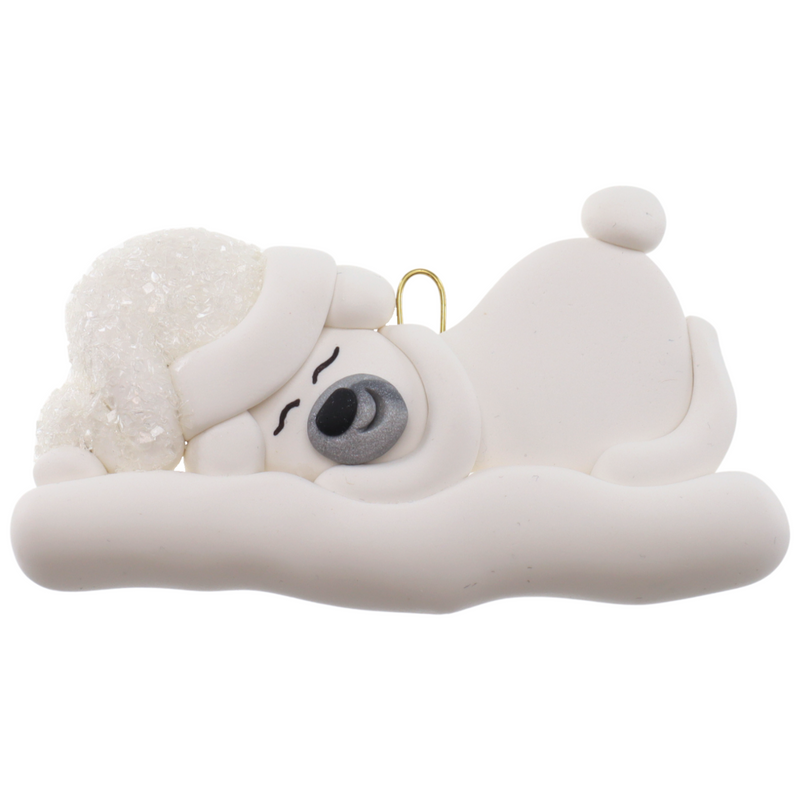 Ornament of white sleeping polar bear baby in a white sparkling hat.