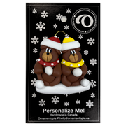 A couple’s ornament of two brown bears in polka dot scarves and hats, on display backing card.