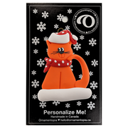 Ornament of orange cat in red and white polka dot Christmas hat and scarf, on display backing card.