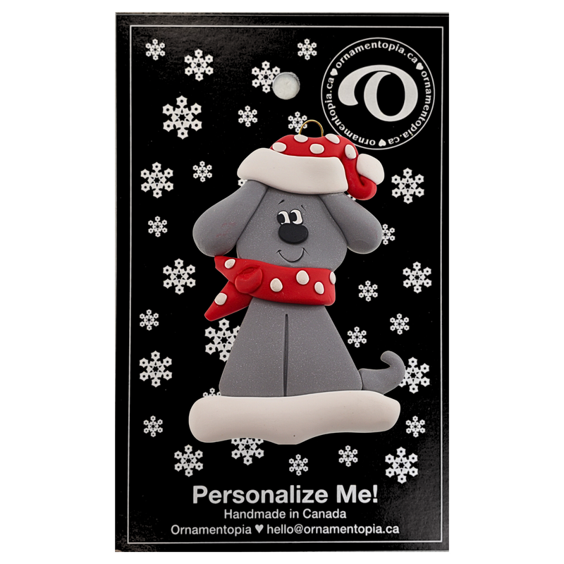 Ornament of grey dog in a red and white polka dot Christmas hat and scarf, on display backing card.