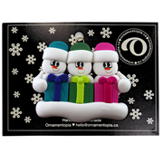 Family ornament with 3 white snowmen in colourful hats holding matching presents, on display backing card.