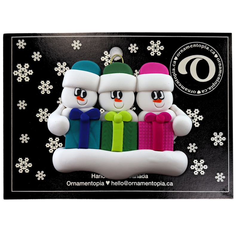 Family ornament with 3 white snowmen in colourful hats holding matching presents, on display backing card.