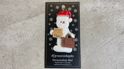 Ornament of white snowman in red hat holding briefcase and files, shown on backing card and Christmas tree.