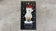 Ornament of white snowman in red hat wearing tool belt with tape measure, shown on backing card and Christmas tree.