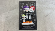 Family ornament with 3 black and white penguins in colourful festive hats, shown on backing card and Christmas tree.
