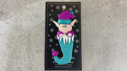 Elf poking out of blue stocking ornament, shown on backing card and Christmas tree.