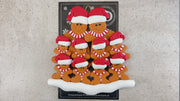 Family ornament with 10 brown gingerbread figures in red Christmas hats, shown on backing card and Christmas tree.