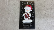 Ornament of white snowman in red hat holding a football, shown on backing card and Christmas tree.