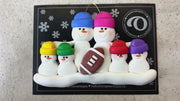 Family ornament with 6 white snowmen in bright hats with a football, shown on backing card and Christmas tree.