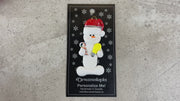 Ornament of white snowman in red hat holding a lightbulb and coil of wire, shown on backing card and Christmas tree.