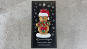 Tan bear in red festive hat holding two candy canes ornament, shown on backing card and Christmas tree.