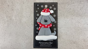 Ornament of grey dog in a red and white polka dot Christmas hat and scarf, shown on backing card and Christmas tree.