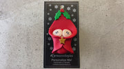 Ornament with twin infant heads poking out of a red baby blanket, shown on backing card and Christmas tree.