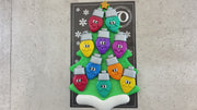 Christmas tree ornament decorated with 10 light bulbs with smiling faces, shown on backing card and decorated Christmas tree.