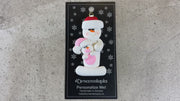 Family ornament with 1 large and 1 infant snowman in pink, shown on backing card and Christmas tree.