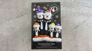 Family ornament with 5 black and white penguins in colourful festive hats, shown on backing card and Christmas tree.
