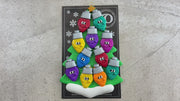 Christmas tree ornament decorated with 11 light bulbs with smiling faces, shown on backing card and decorated Christmas tree.
