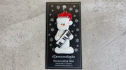 Ornament of white snowman in red hat holding a piano keyboard, shown on backing card and Christmas tree.