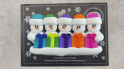 Family ornament with 5 white snowmen in colourful hats holding matching presents, shown on backing card and Christmas tree.