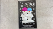 Family ornament with 2 snowmen in bright hats, one pregnant, shown on backing card and Christmas tree.