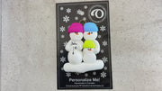 Family ornament with 3 snowmen in bright hats, one pregnant, shown on backing card and Christmas tree.