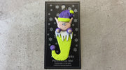 Elf poking out of green stocking ornament, shown on backing card and Christmas tree.