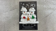 Family ornament with 2 large and 1 small snowmen in hats, holding holiday objects, shown on display card and Christmas tree.