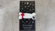 Ornament of dog bone with ribbon and paw print,shown on backing card and decorated Christmas tree.