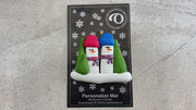 Ornament with 2 snowmen in colourful scarves and hats, hemmed by Christmas trees, shown on backing card and Christmas tree.