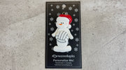 Ornament of white snowman in red hat holding a volleyball, shown on backing card and Christmas tree.