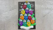 Christmas tree ornament decorated with 12 light bulbs with smiling faces, shown on backing card and decorated Christmas tree.