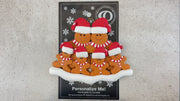 Family ornament with 6 brown gingerbread figures in red Christmas hats, shown on backing card and Christmas tree.