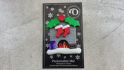 Vibrant fireplace ornament with holly and presents, displaying 2 red stockings, shown on backing card and Christmas tree.