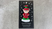 Red and green elf ornament, shown on backing card and Christmas tree.