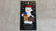 Ornament of white snowman in red hat holding a briefcase and law books, shown on backing card and Christmas tree.