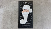 Ornament with infant head in a white glitter hat poking out of a white glitter stocking, shown on backing card and Christmas tree.