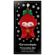 Ornament with twin infant heads poking out of a red baby blanket, on display backing card.