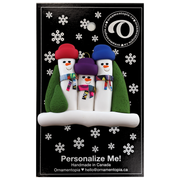 Family ornament with 3 snowmen in colourful scarves and hats, hemmed by Christmas trees, shown on display backing card.