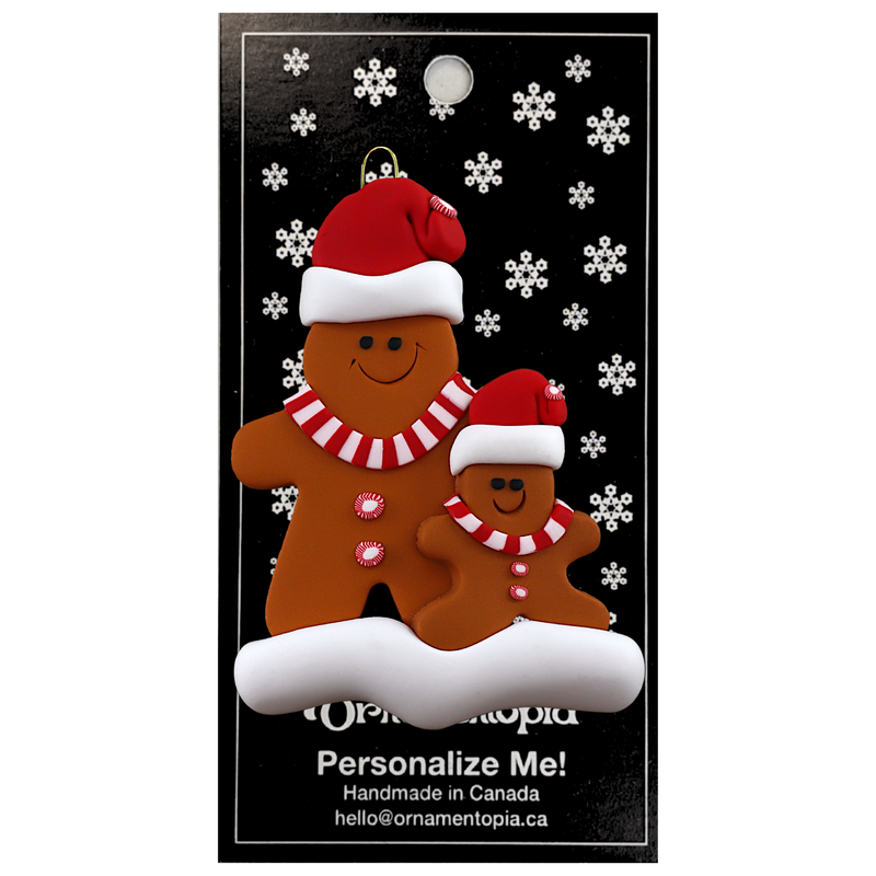 Family ornament with 1 large and 1 small brown gingerbread figure in red Christmas hats, on display backing card.