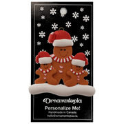 Family ornament with 1 large and 2 small brown gingerbread figures in red Christmas hats, on display backing card.