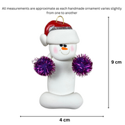 Ornament of white snowman in red hat holding purple cheerleader pom-poms, graphed to show size (4x9cm).