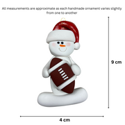 Ornament of white snowman in red hat holding a football, graphed to show size (4x9cm).