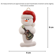 Ornament of white snowman in red hat holding a colourful guitar, graphed to show size (4x9cm).