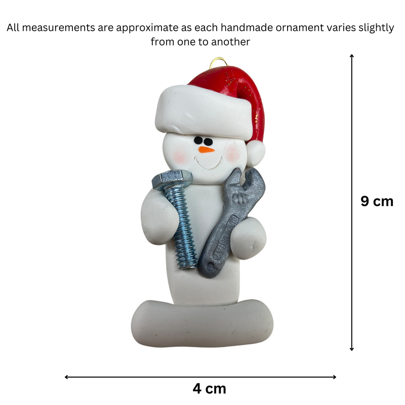 Ornament of white snowman in red hat holding a wrench and a screw, graphed to show size (4x9cm).