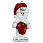 Ornament of white snowman in red hat holding a shiny red apple, personalized with name.