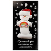 White snowman with small rainbow and red festive hat ornament, on display backing card.