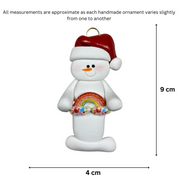 White snowman with small rainbow and red festive hat ornament, graphed to show size (4x9cm).