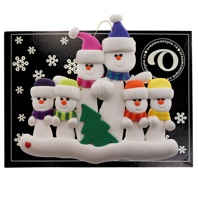 Family ornament with 6 white snowmen in bright scarves, with green Christmas tree, on display card backing.