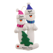 Family ornament with 2 white snowmen in bright scarves, with green Christmas tree, personalized with names.