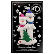 Family ornament with 2 white snowmen in bright scarves, with green Christmas tree, on display card backing.